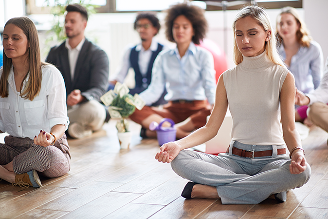 Group of young professionals sitting together in a meditation pose