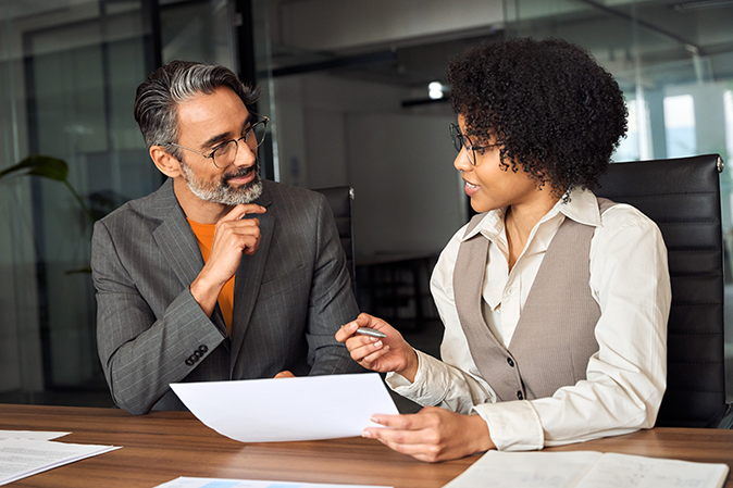 Young woman going over a document with a senior man in an office