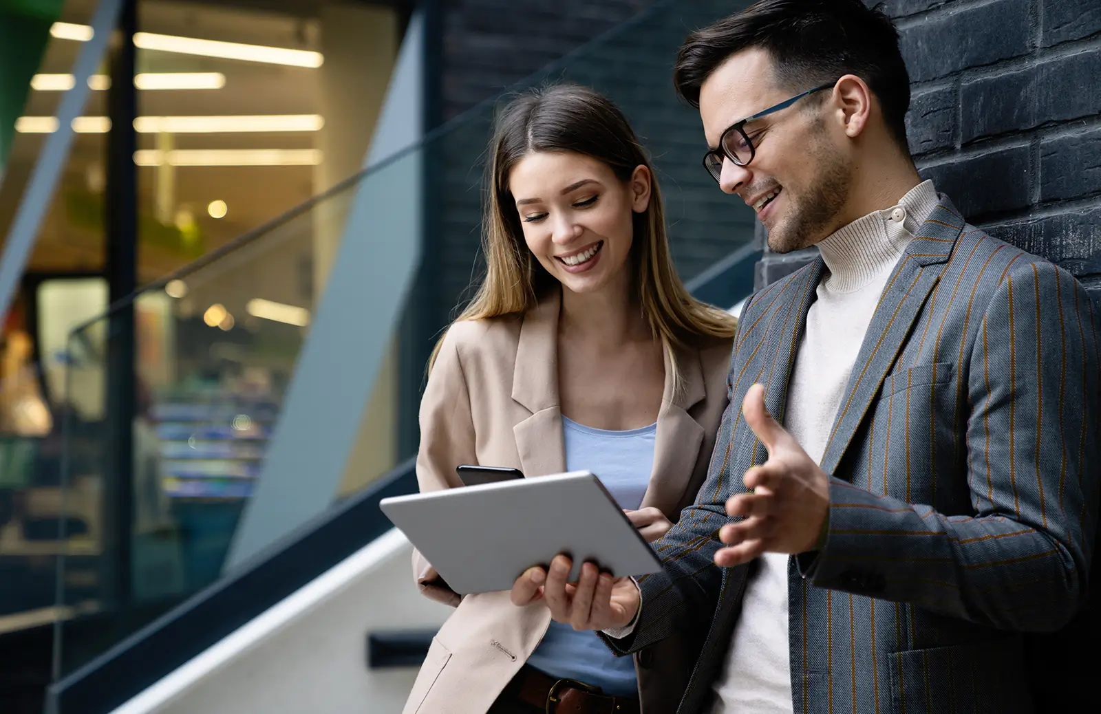 A young professional woman and man working together while discussing something on a tablet