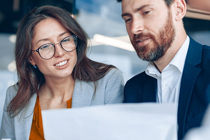 Close up of smiling businessmen discussing documents with graphs and charts in a modern office.