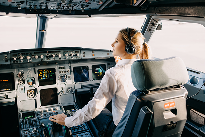 Young woman pilot sitting in front of the controls in the cockpit