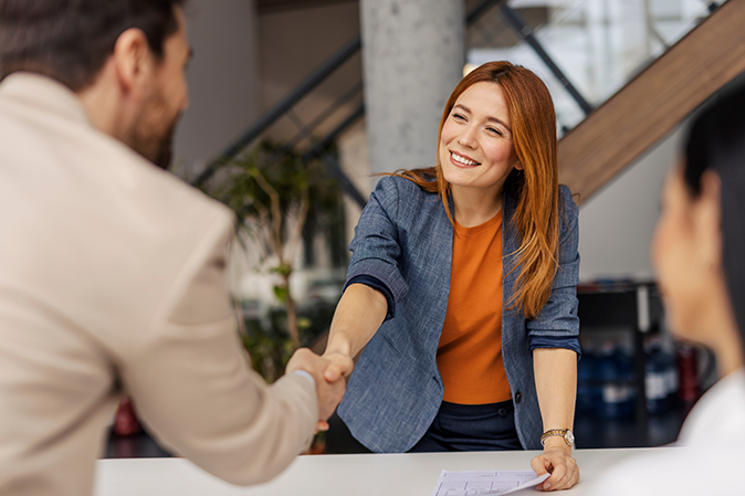 Young woman shaking hands with a man in an office