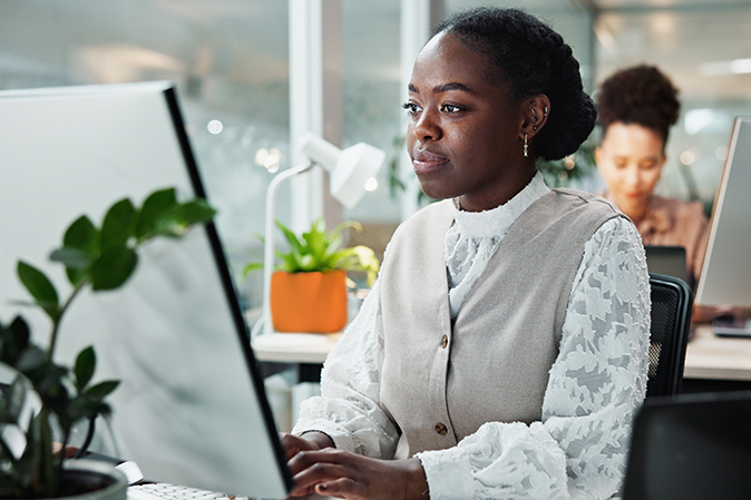 Young professional woman in an office typing on a computer