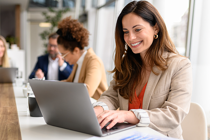 Young woman dressed professionally typing on a laptop in an office