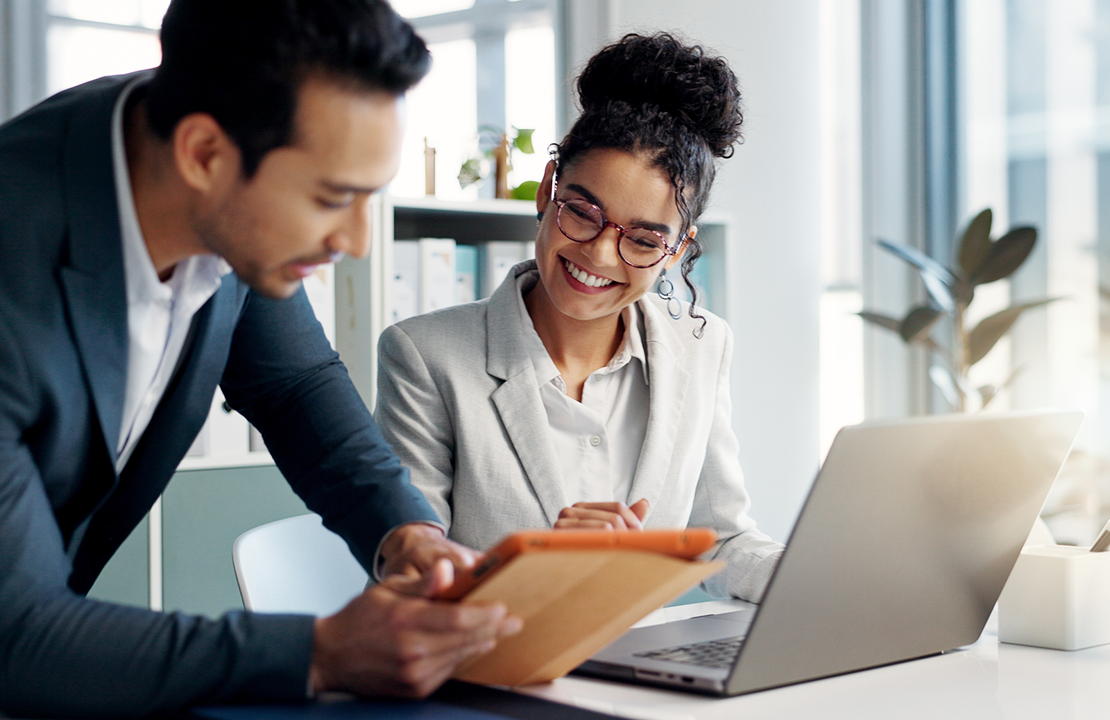 Young woman paralegal working on a laptop with a lawyer holding a tablet