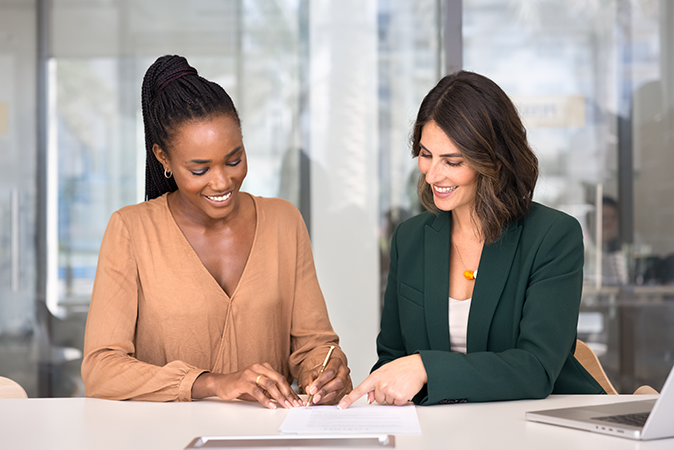 Middle woman working with a young woman who is writing a document