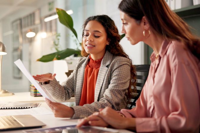 Two women chatting at a desk