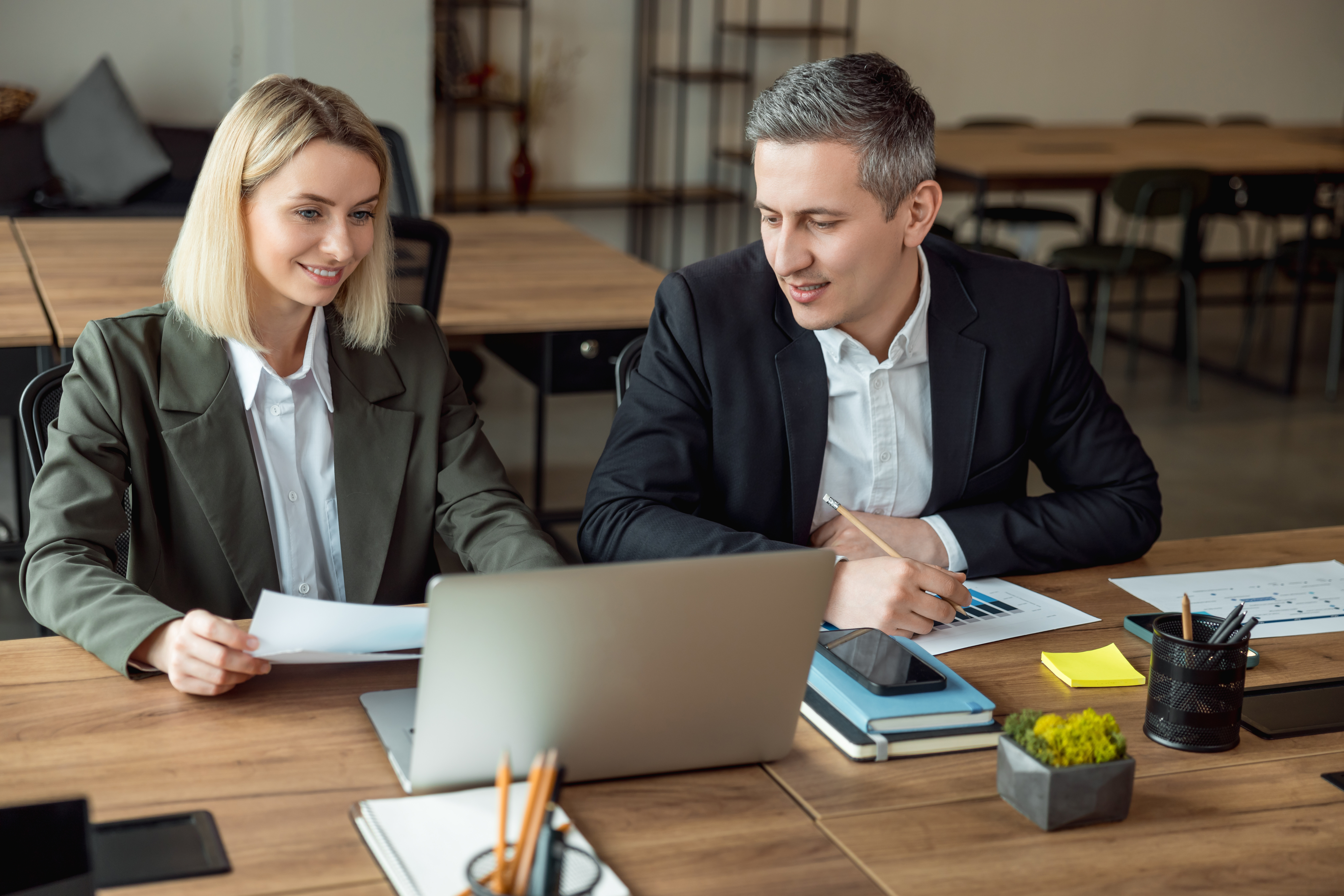 Professional woman and man looking at a document and laptop