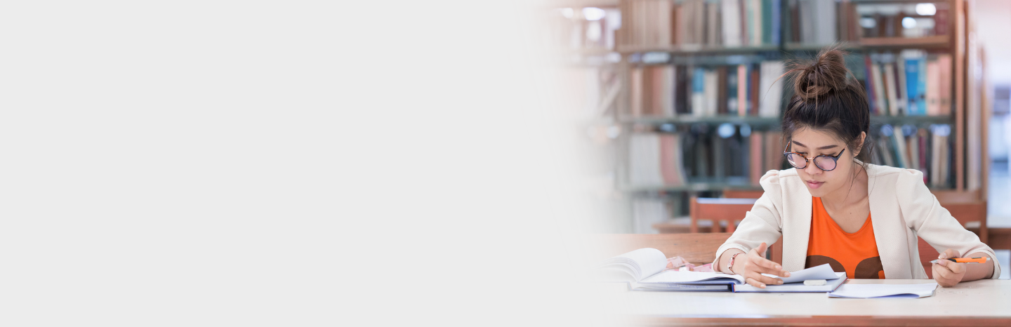 female student studying and taking notes in library