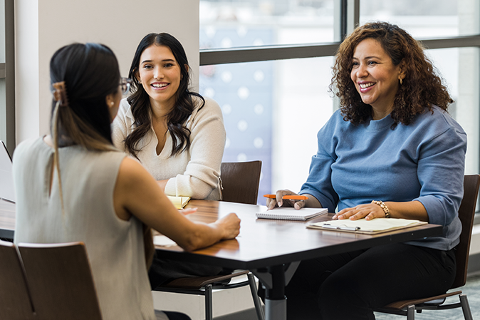 The businesswomen meet with their marketing team lead to review their business strategy going into the new quarter.