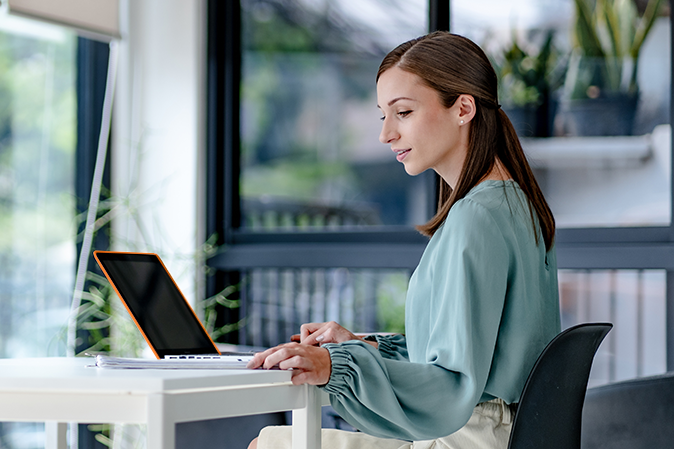 Woman sitting in brightly lit office with a laptop doing BARBRI SQE2 Prep Demo