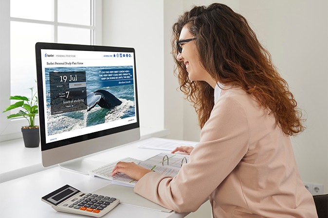 Smiling woman working at home or office sitting at desk working on a computer.