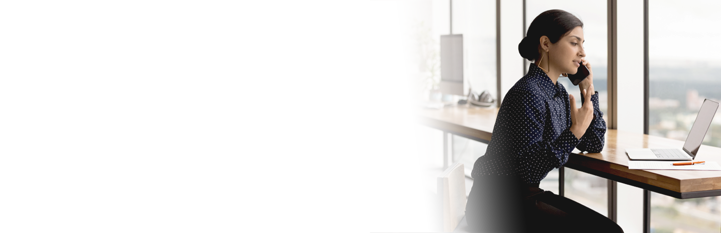 Young woman chatting on mobile phone while looking at laptop screen