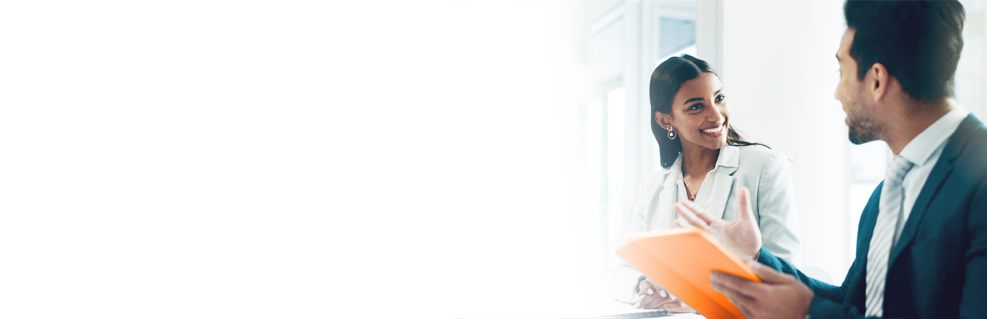 Young man holding a tablet while speaking to a young woman in an office