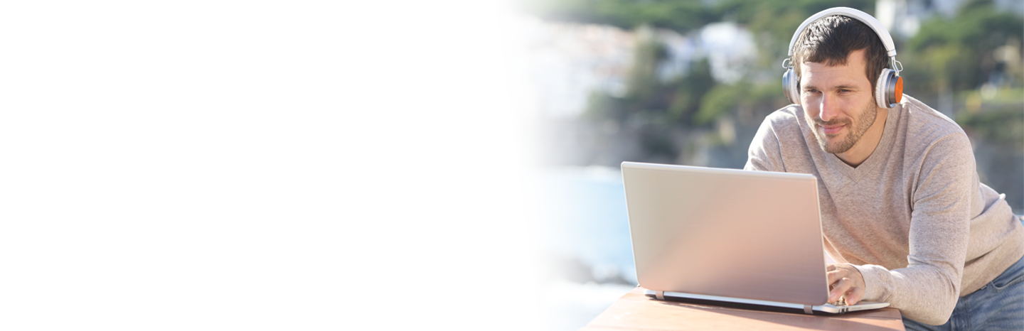 Young man listening while working on laptop outside