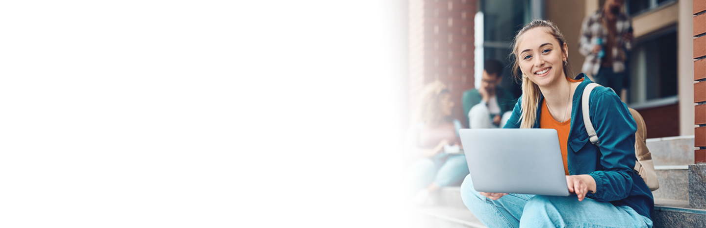 Young woman outside on university steps using laptop