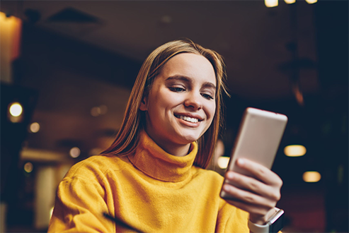 Young woman smiling while using a mobile device