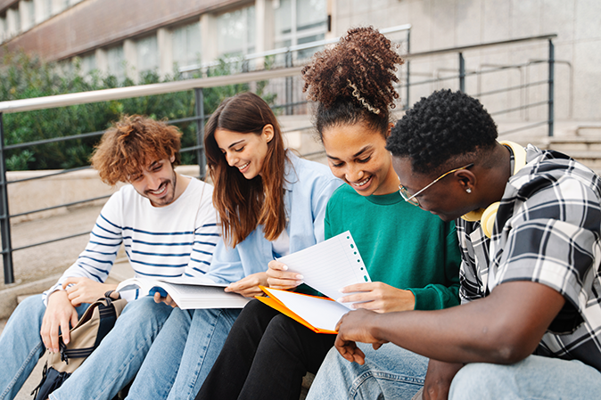 Four students studying together outside on university steps