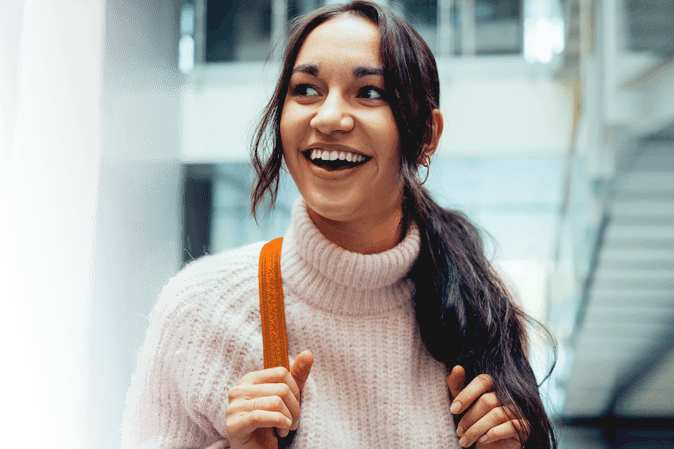 Young woman smiling on campus wearing a backpack