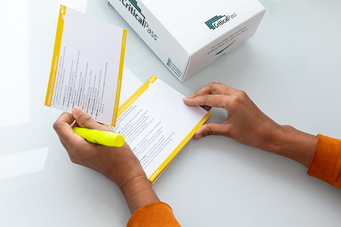 Person holding a highlighter while reviewing CriticalPass flashcards