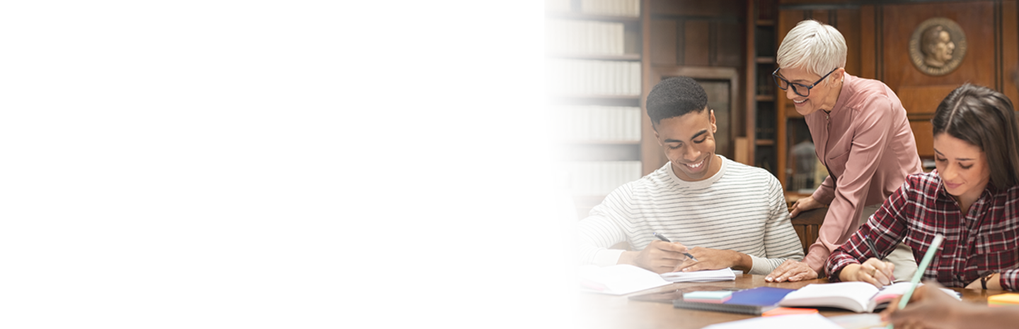 Professor working with a couple of students sitting at a table in a library