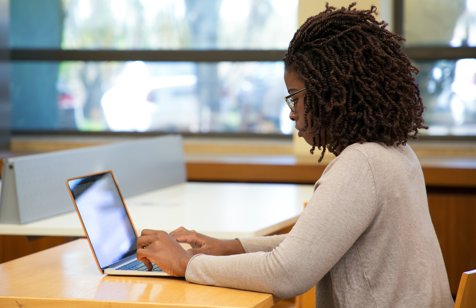 Young woman taking a test on a laptop in a classroom