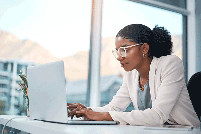 Young woman dressed professionally on a laptop in an office