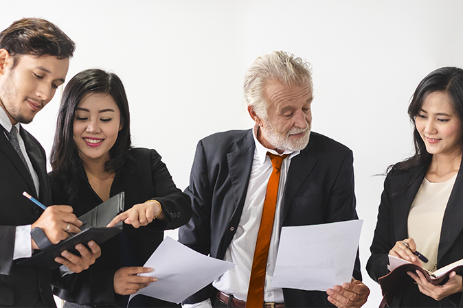 Marketing team consulting sales plan with supervisor senior manager in conference room before presenting to client.