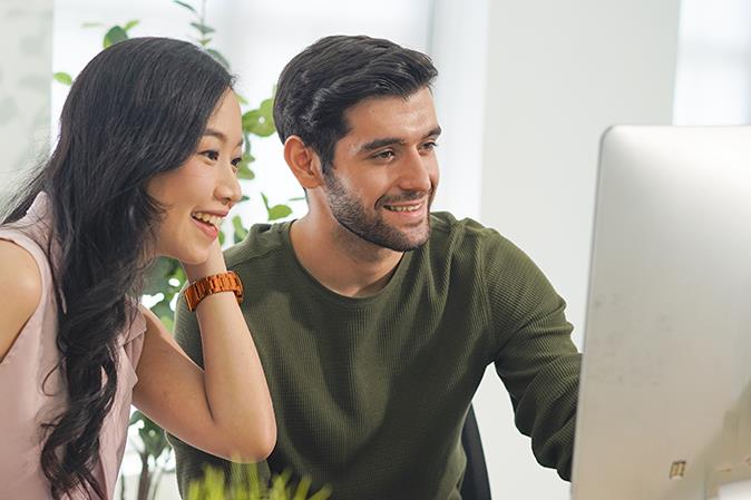 male and female colleague look at desktop computer