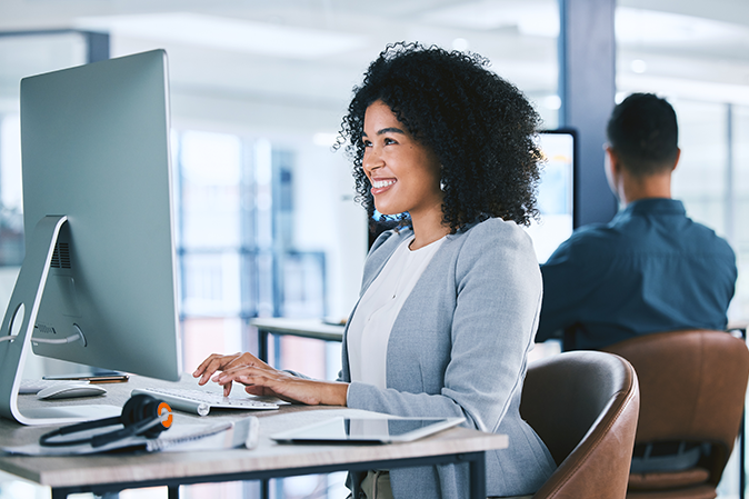 Woman, typing at computer with online tech support and email, consultant at desk with smile at customer service agency. Contact center, communication and happy female agent with feedback and help.