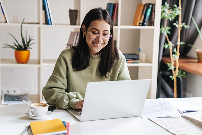 Young woman smiling while working on laptop at a desk